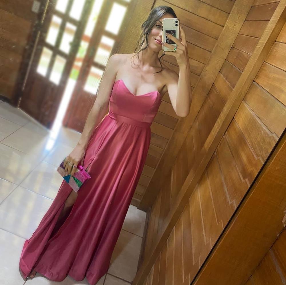 Vestido longo rosa em tecido acetinado, tomara que caia com decote coração, saia fluida e fenda lateral.