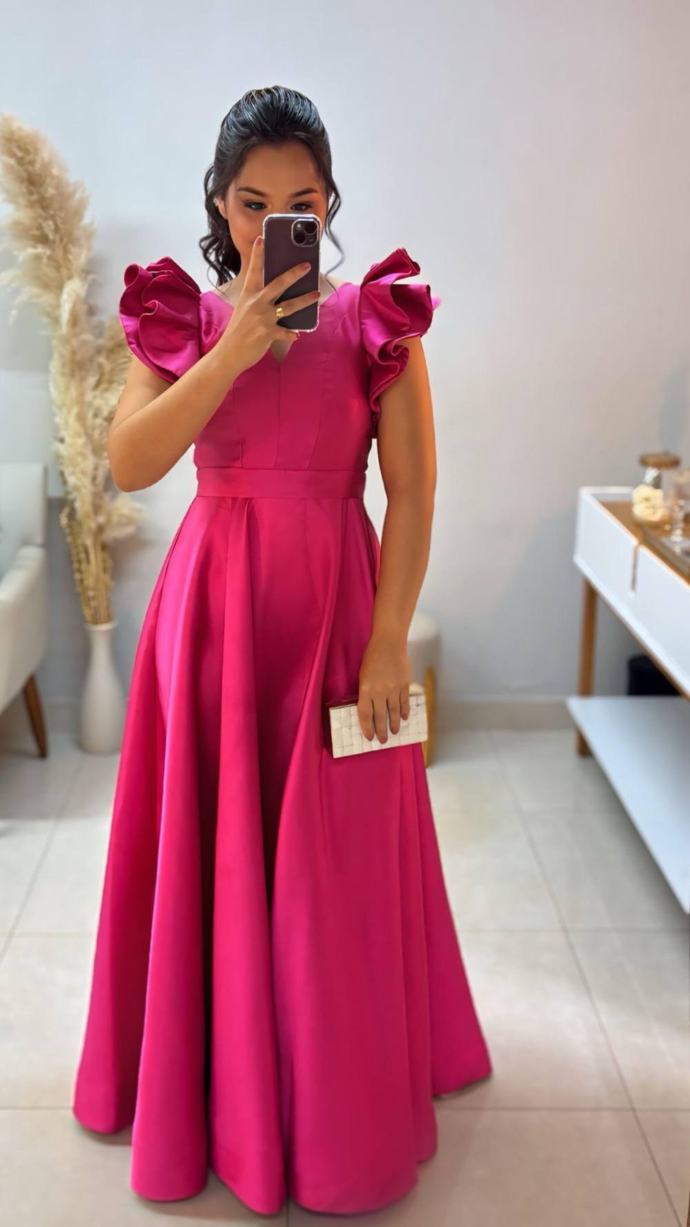 Vestido longo fúcsia de tecido encorpado, decote V, mangas curtas estruturadas com babados e saia ampla evasê.