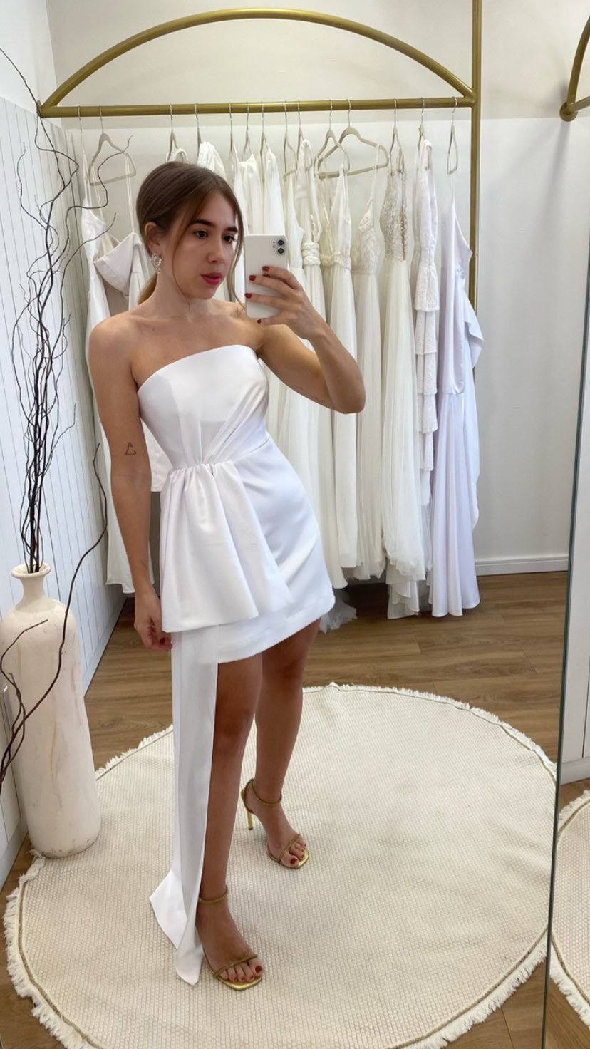 Vestido curto branco tomara que caia com efeito drapeado na cintura e cauda lateral.