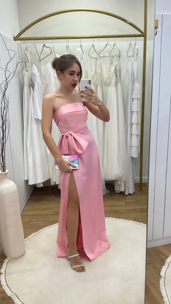 Vestido longo rosa tomara que caia, com laço na cintura, caimento reto e fenda frontal destacada.