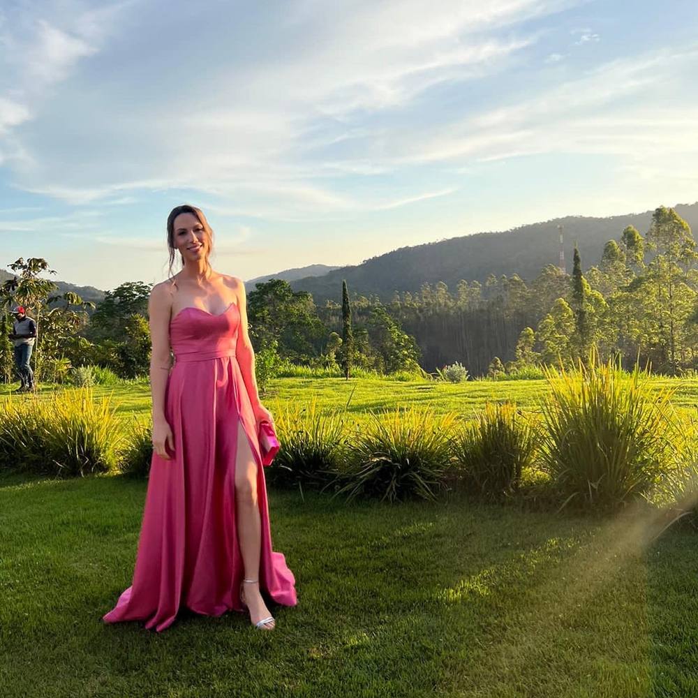 Vestido longo fúcsia de cetim, tomara que caia, com fenda profunda e saia fluida.