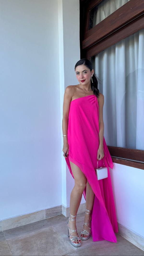 Vestido longo fúcsia em tecido fluido, com decote de um ombro só e fenda alta na saia.