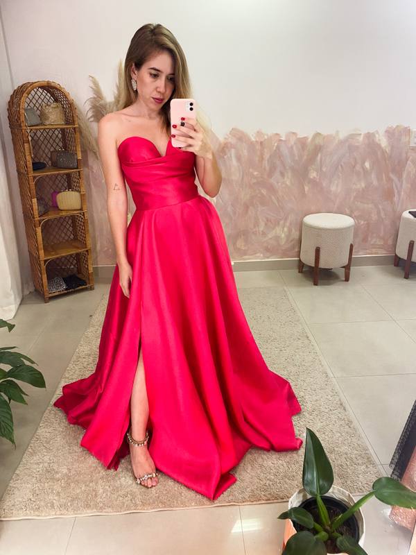 Vestido longo fúcsia em tecido estruturado, modelo tomara que caia com saia volumosa e fenda frontal.