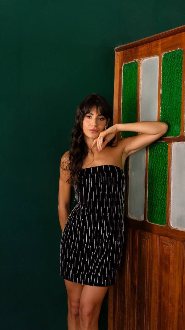 Vestido curto preto tomara que caia, caimento reto com aplicação de brilhos em linhas verticais.