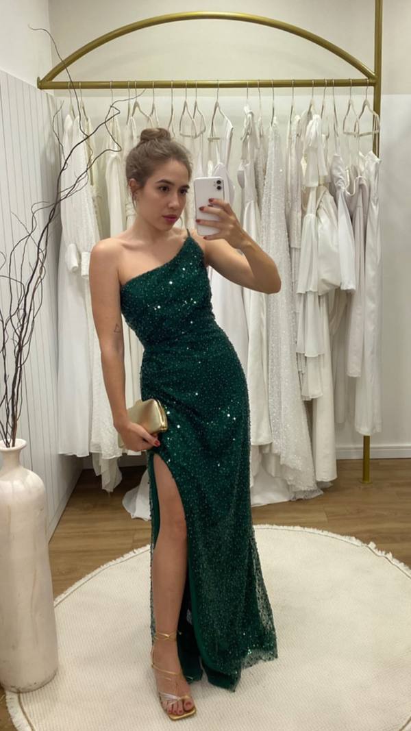 Vestido longo verde de um ombro, totalmente trabalhado em brilho, com caimento ajustado e fenda lateral.