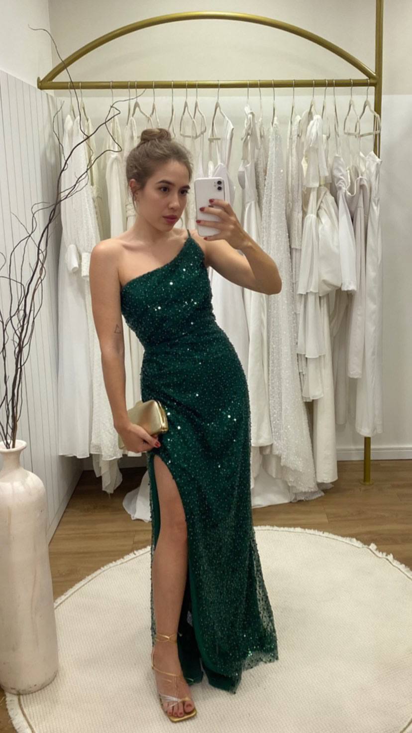 Vestido longo verde de um ombro, totalmente trabalhado em brilho, com caimento ajustado e fenda lateral.