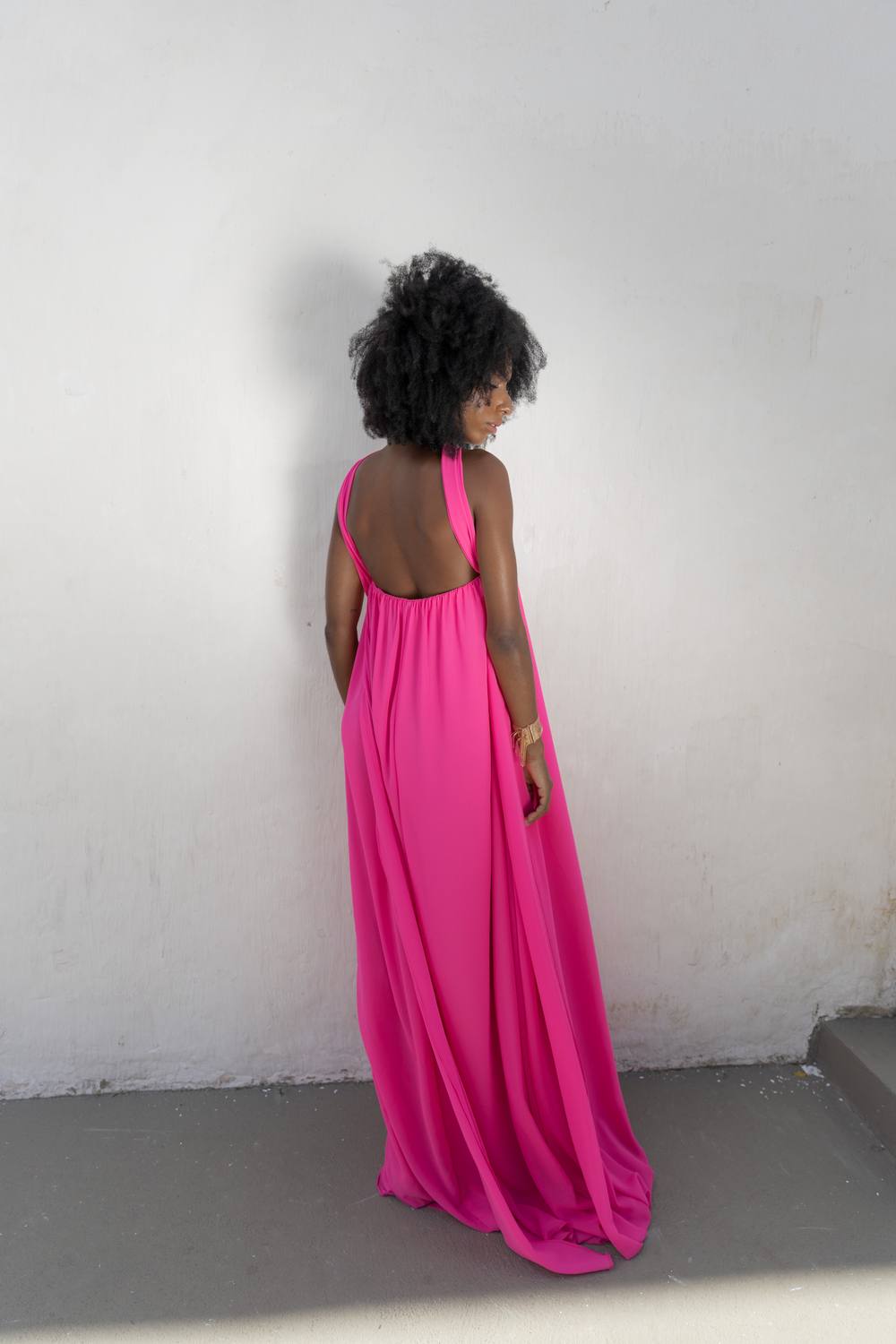 Vestido longo fúcsia fluido, com costas nuas e caimento leve.