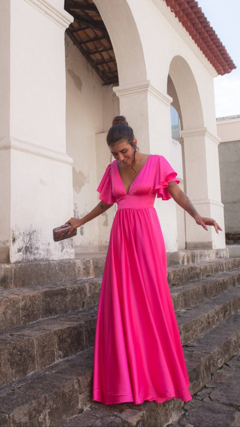 Vestido longo fúcsia de caimento fluido, com decote V profundo e mangas curtas estilo babado.