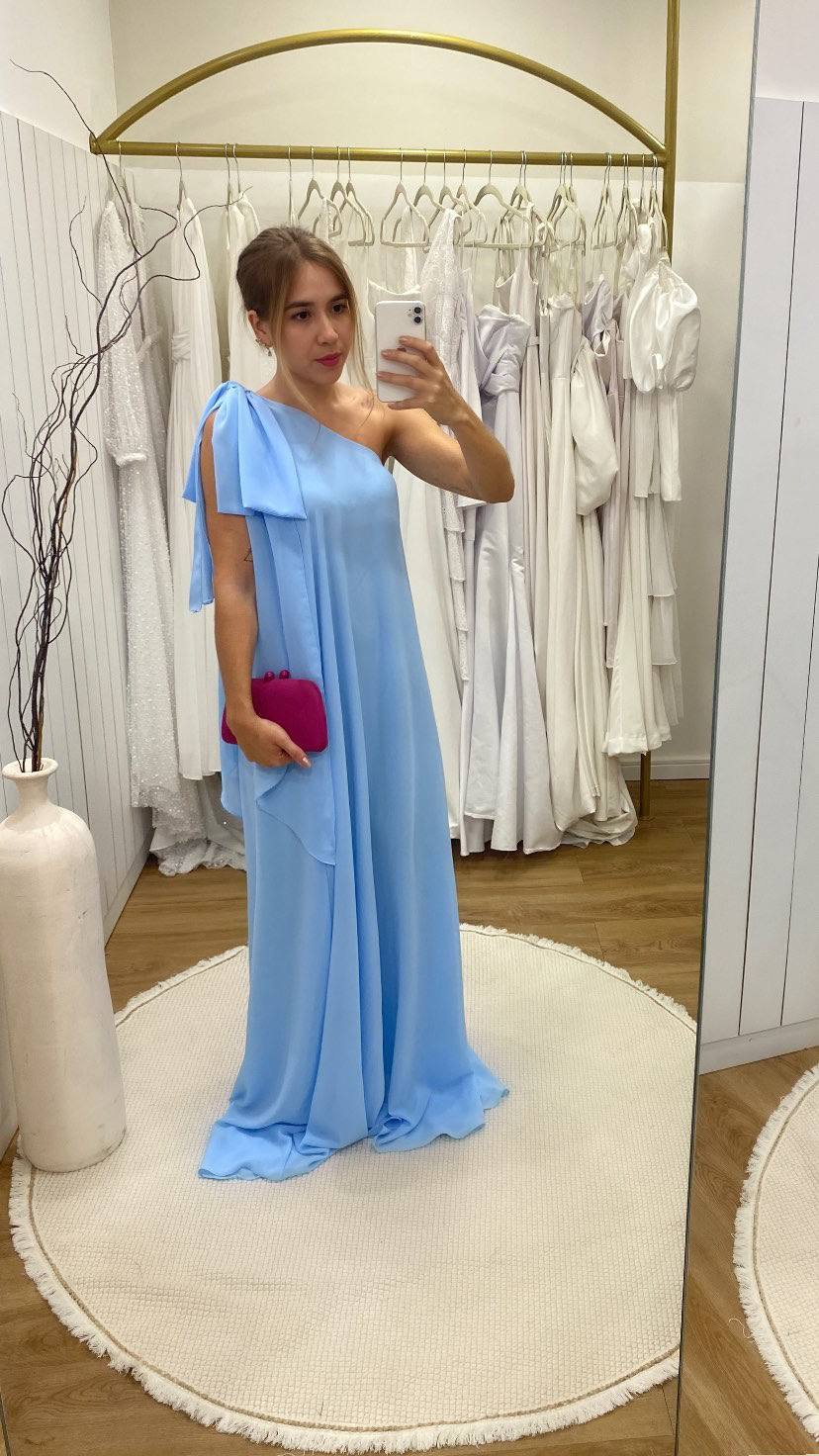Vestido longo azul claro de um ombro só, em tecido leve de caimento fluido e solto.