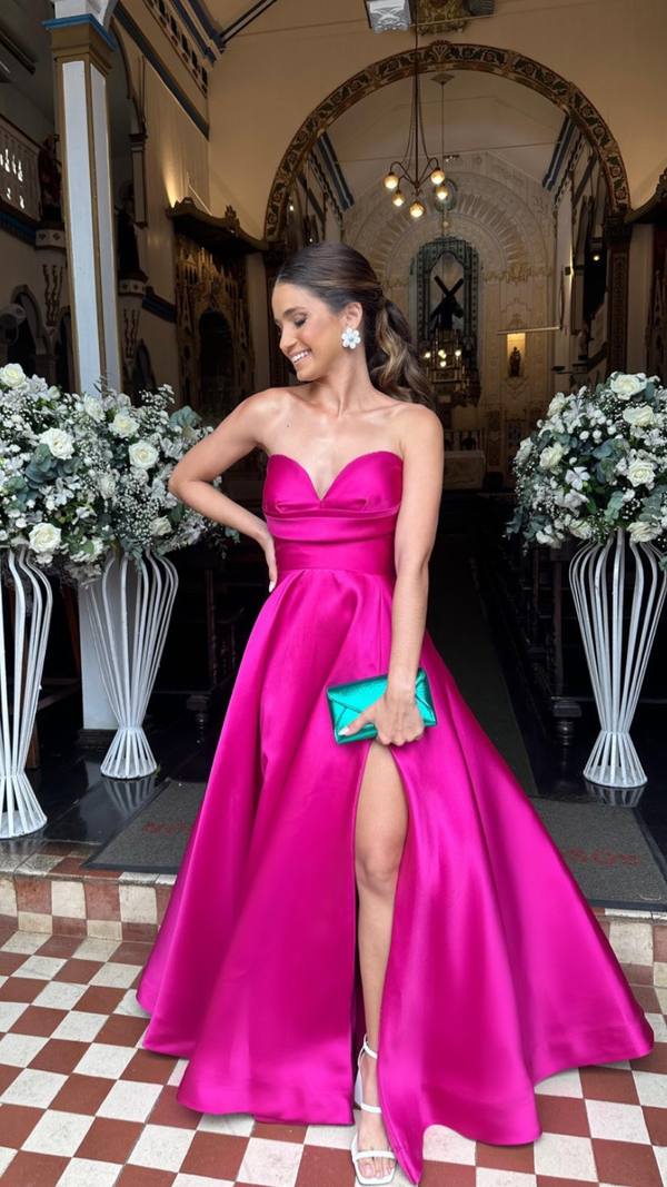 Vestido longo fúcsia tomara que caia em tecido estruturado, com saia ampla e fenda frontal destacada.