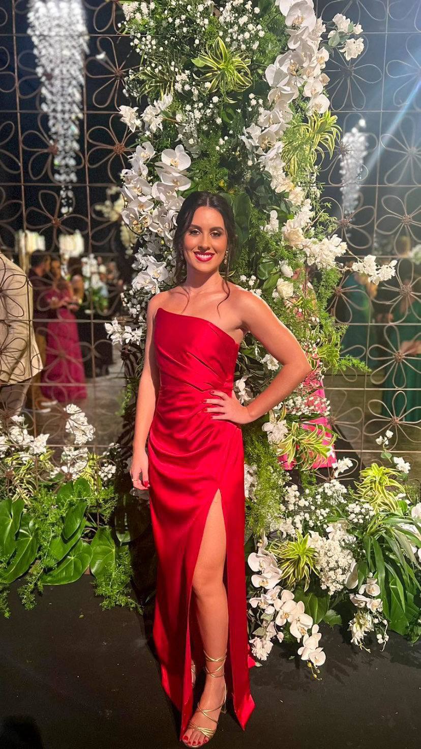 Vestido longo vermelho em cetim, decote tomara que caia, caimento ajustado e fenda frontal na saia.