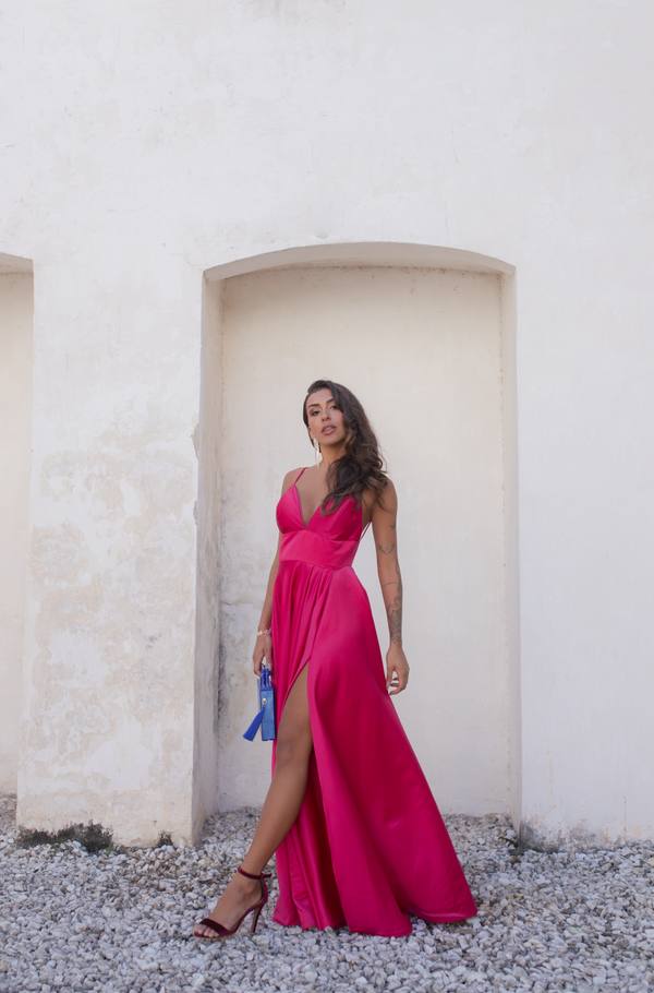 Vestido longo fúcsia de cetim, decote V com alças finas, saia fluida e fenda lateral.