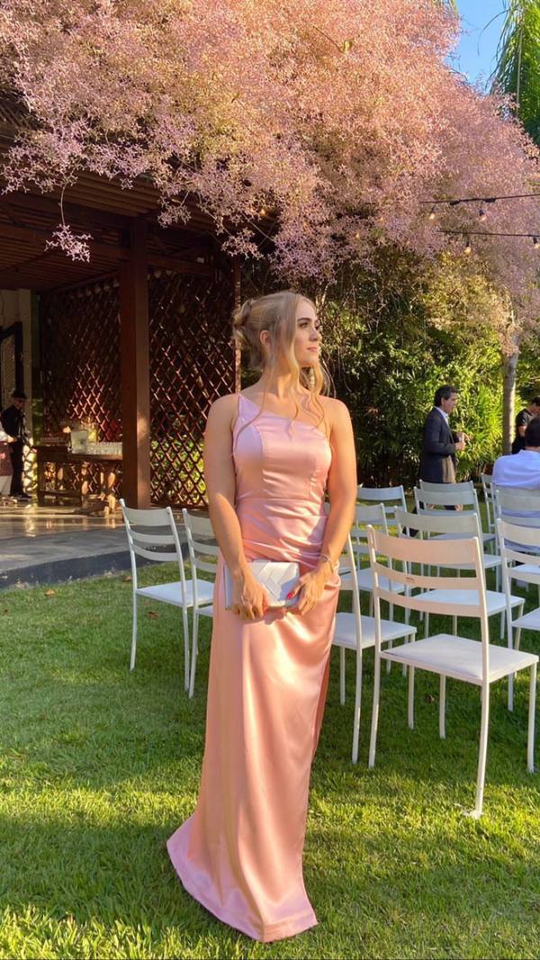Vestido longo rosé de cetim, com decote de um ombro e caimento reto.