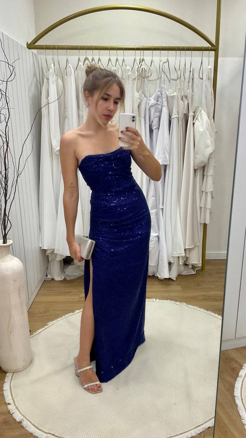 Vestido longo azul escuro de paetês, decote tomara que caia, caimento reto e fenda lateral.
