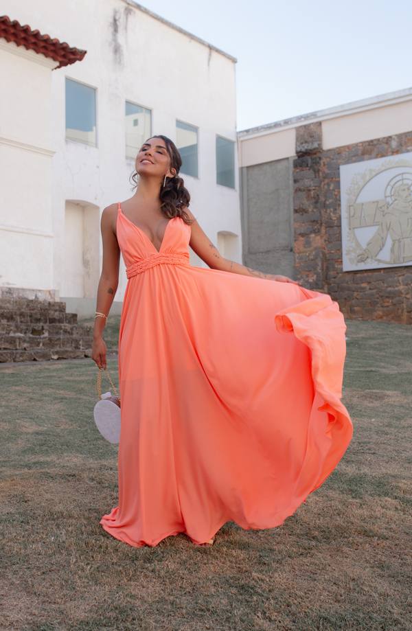 Vestido longo coral de alças finas e decote V, em tecido fluido com detalhe trançado abaixo do busto e saia ampla.