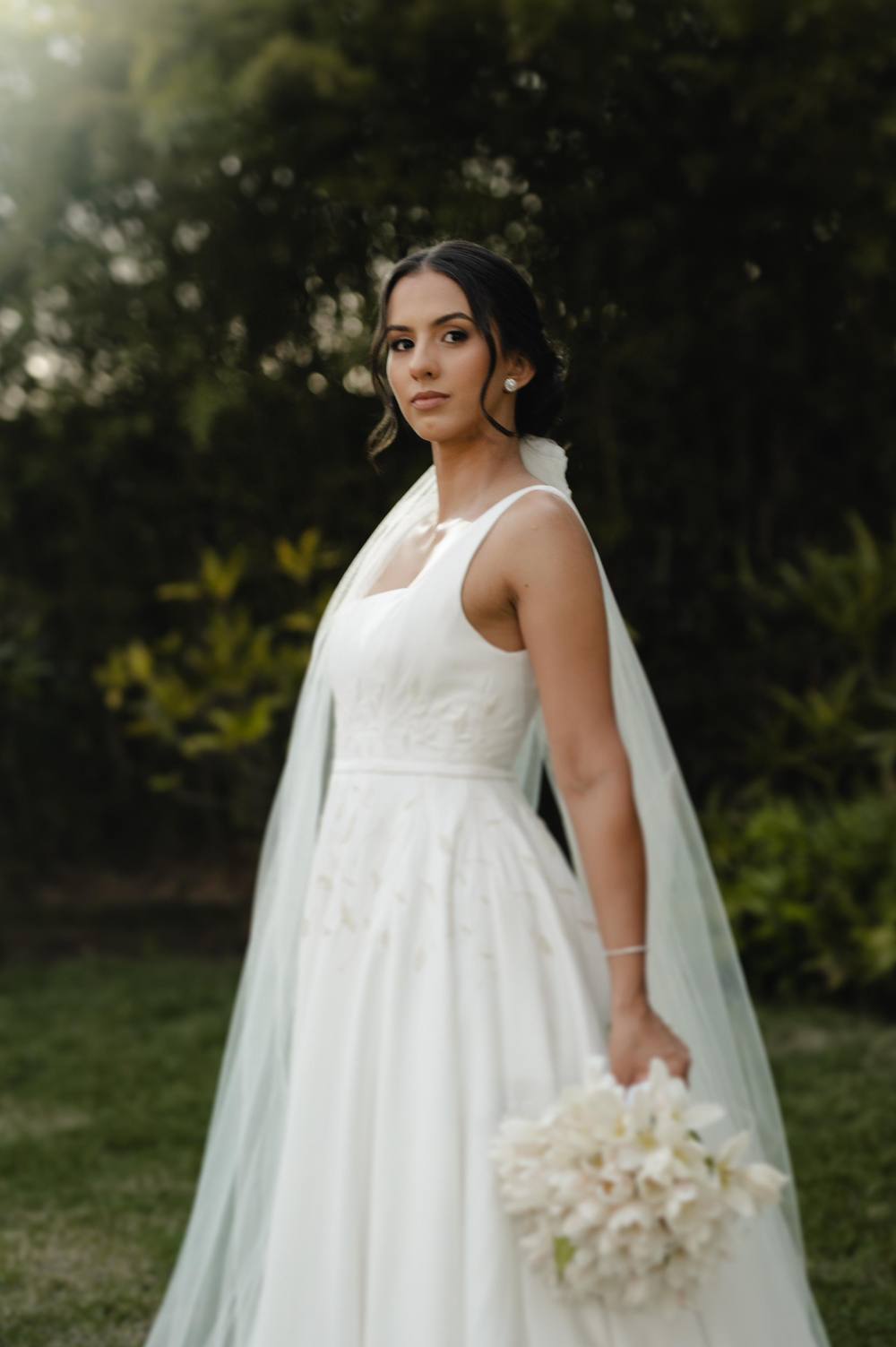 Vestido de noiva branco evasê de alça fina, com buquê