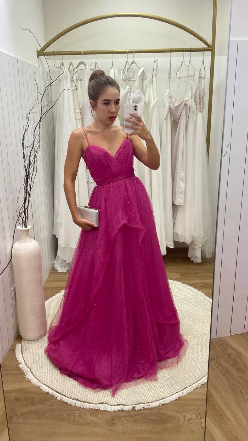 Vestido longo fúcsia em tule com brilho, alças finas, cintura marcada e saia volumosa estilo princesa.