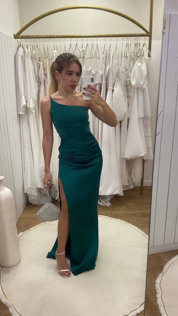Vestido longo verde de cetim, decote de um ombro só, caimento ajustado ao corpo e fenda lateral na saia.