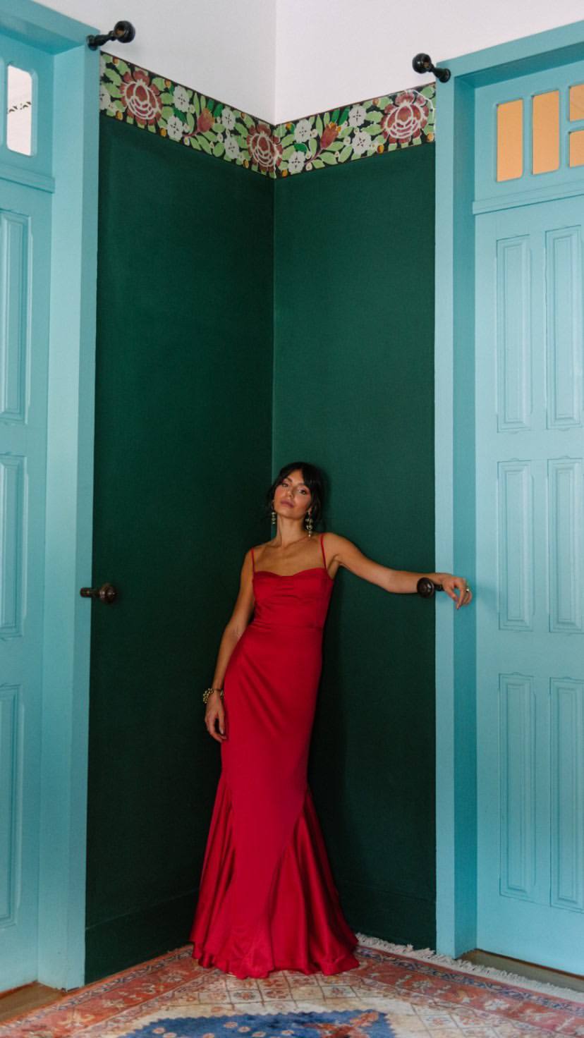 Vestido longo vermelho de alça fina, corpete estruturado e saia estilo sereia de caimento fluido.