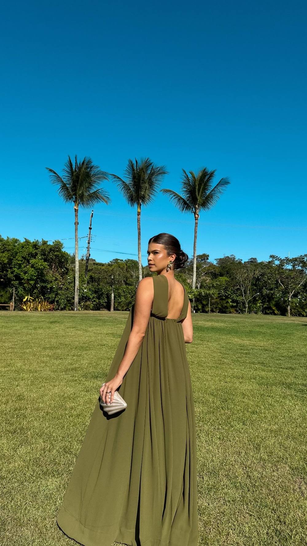 Vestido longo verde oliva fluido, com alças largas, costas nuas e caimento leve solto ao corpo.
