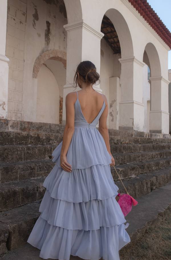 Vestido longo azul claro de chiffon com alças finas, decote profundo nas costas e saia fluida em camadas.