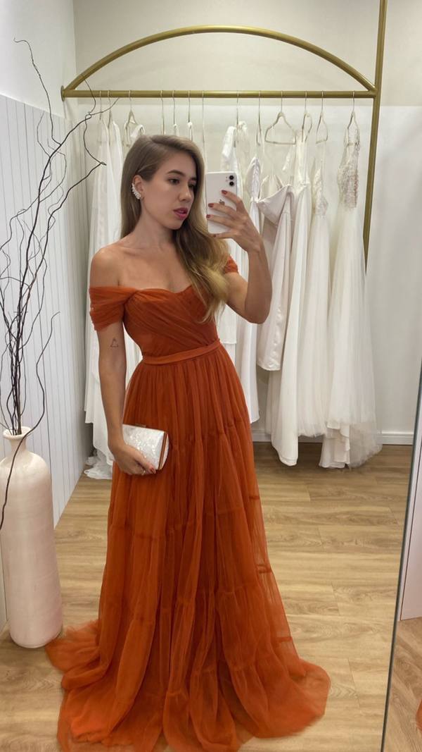Vestido longo terracota de tule, decote ombro a ombro e saia fluida em camadas.