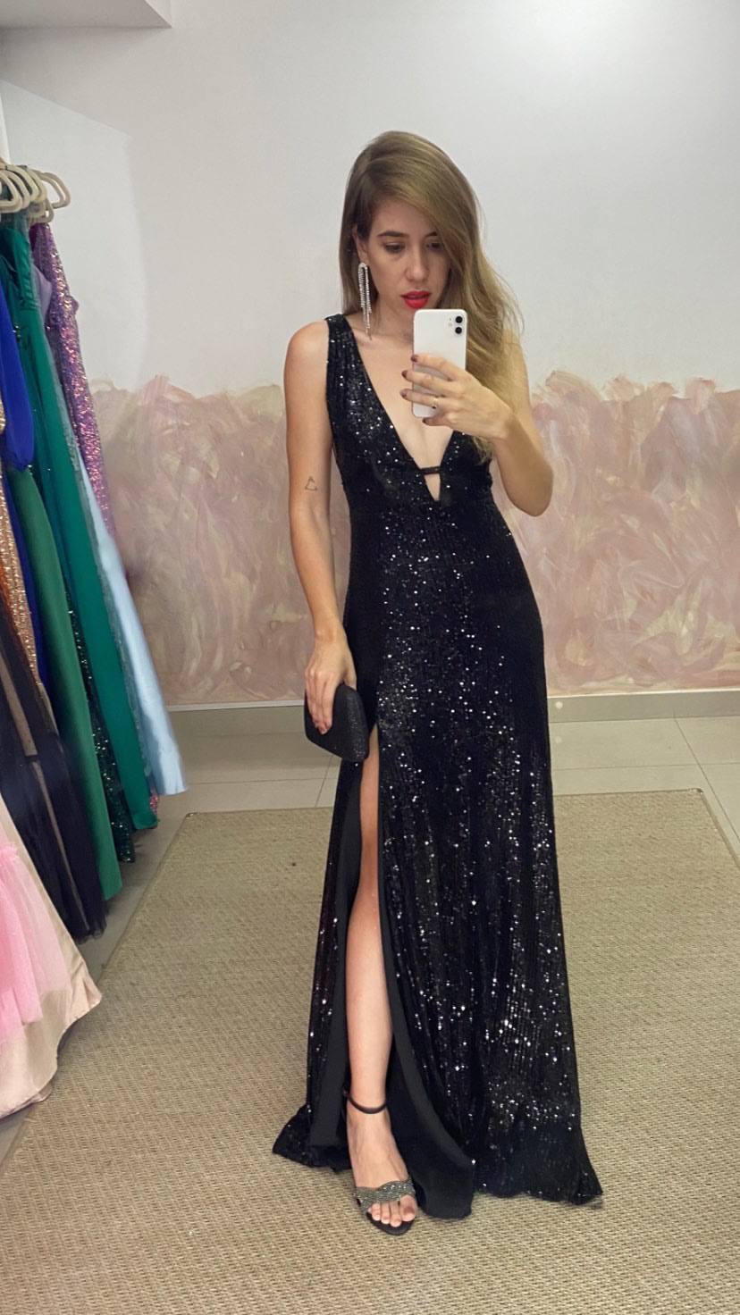 Vestido longo preto de paetês, decote V profundo, fenda lateral e caimento ajustado.