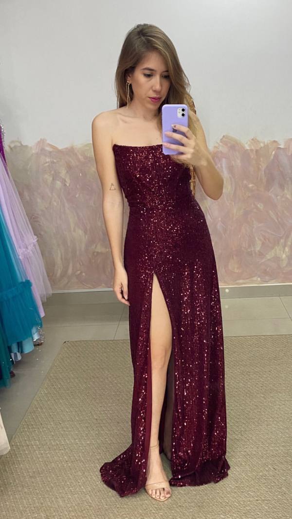 Vestido longo marsala com brilho de paetês, decote tomara que caia, corte reto e fenda alta.