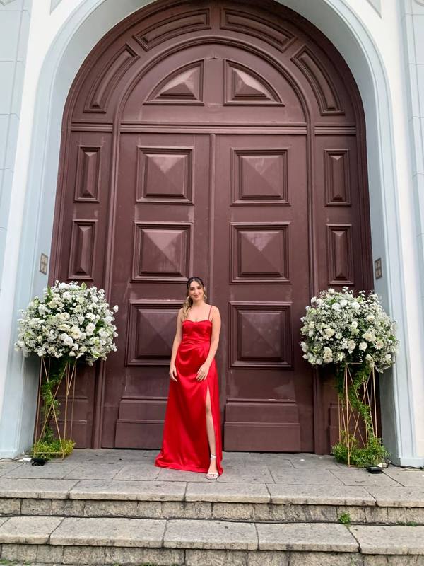 Vestido longo vermelho de cetim, com alças finas, saia fluida e fenda lateral.