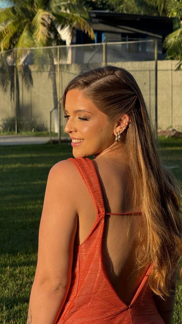 Vestido terracota de tecido brilhante, com decote profundo nas costas nuas e alças largas.