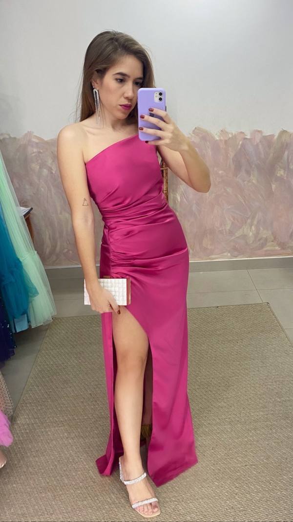 Vestido longo fúcsia de cetim, modelo um ombro com fenda lateral profunda e detalhe drapeado na cintura.