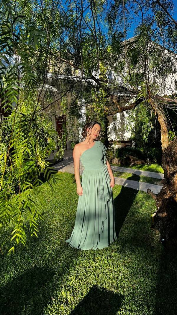 Vestido longo verde claro de um ombro só em tecido fluido, com detalhe de babados na saia.