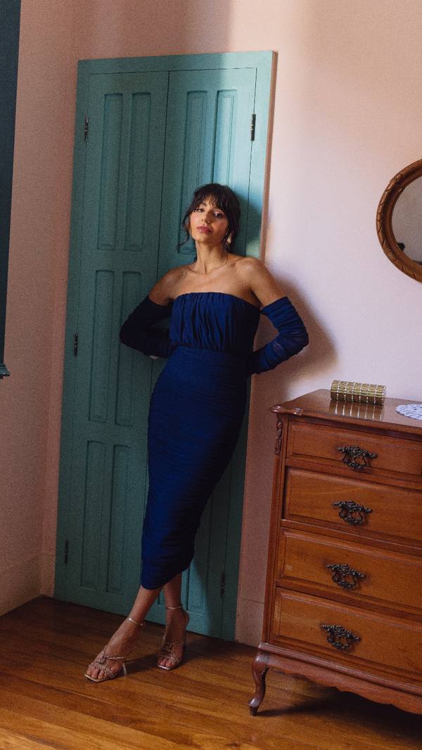 Vestido midi azul escuro ajustado ao corpo, modelo tomara que caia com mangas longas e tecido franzido.