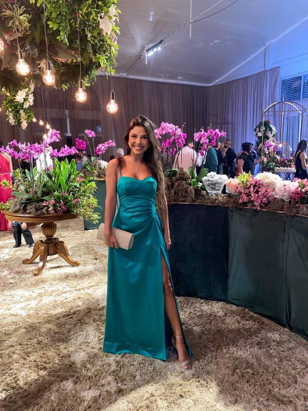 Vestido longo verde de alça fina em tecido acetinado, com drapeado na cintura e fenda lateral.