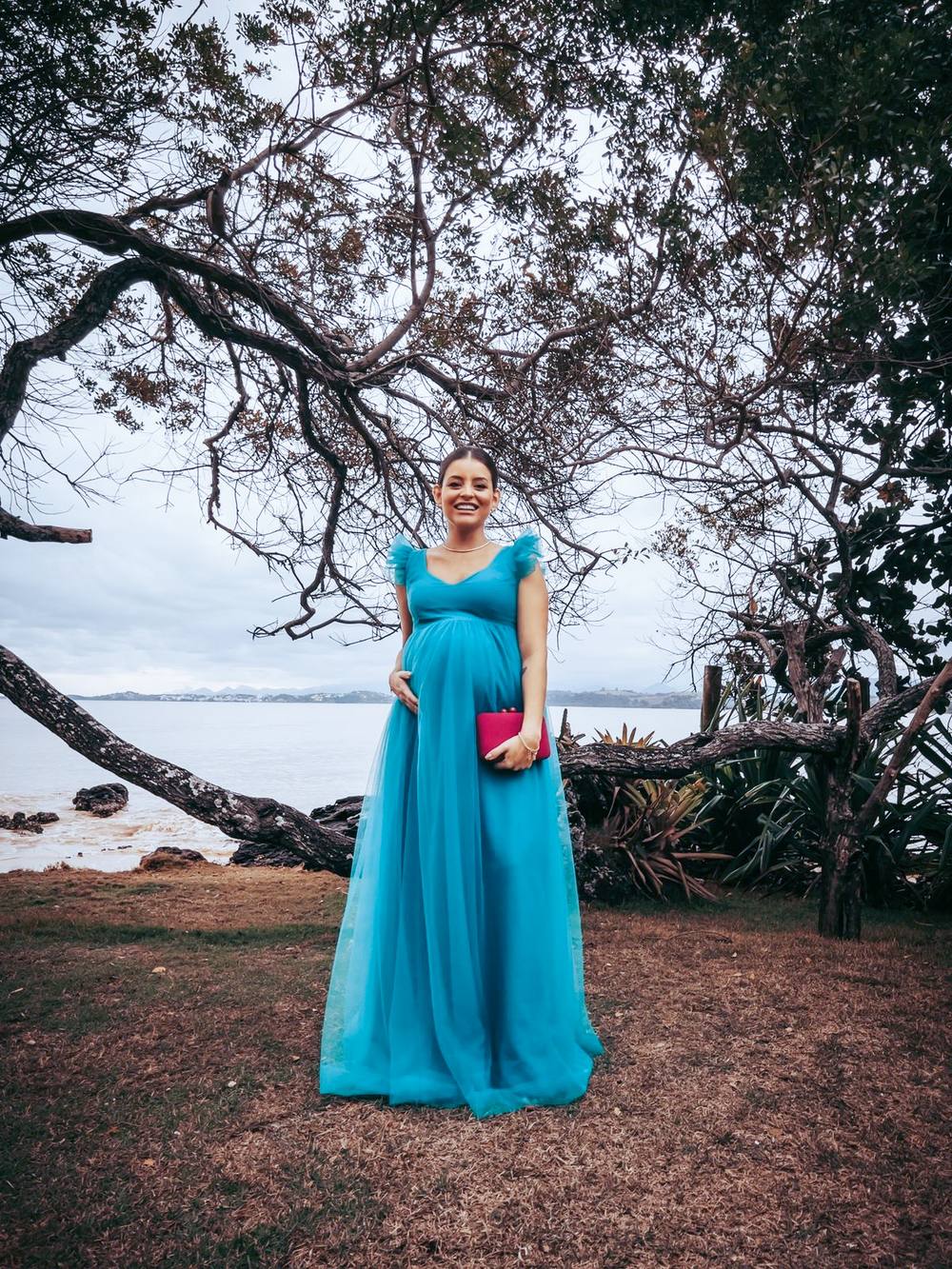 Vestido longo azul tiffany em tule, com decote V, detalhes de babados nos ombros e saia fluida.