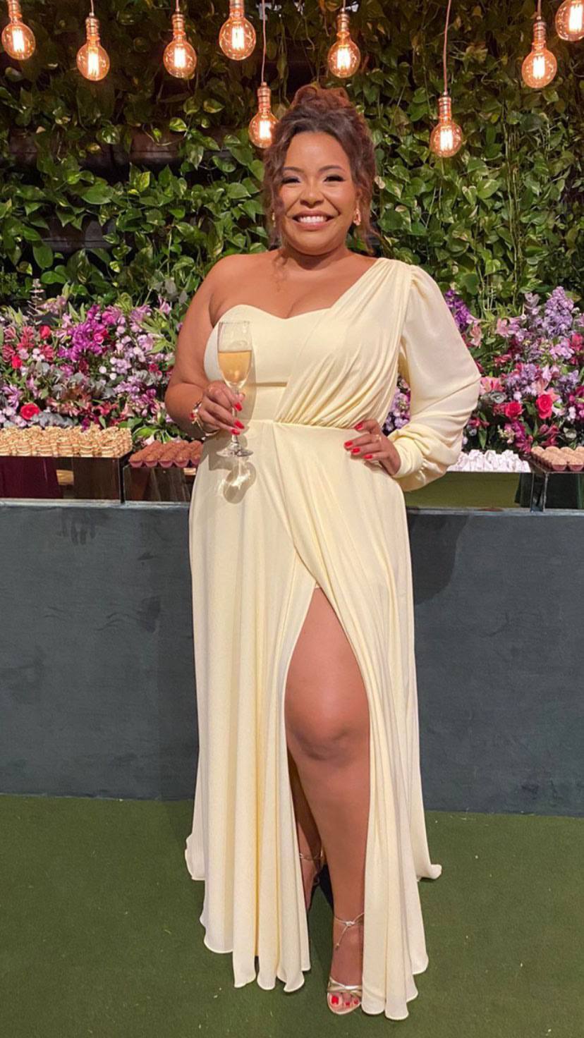 Vestido longo amarelo claro de um ombro só com manga longa, saia fluida e fenda frontal.