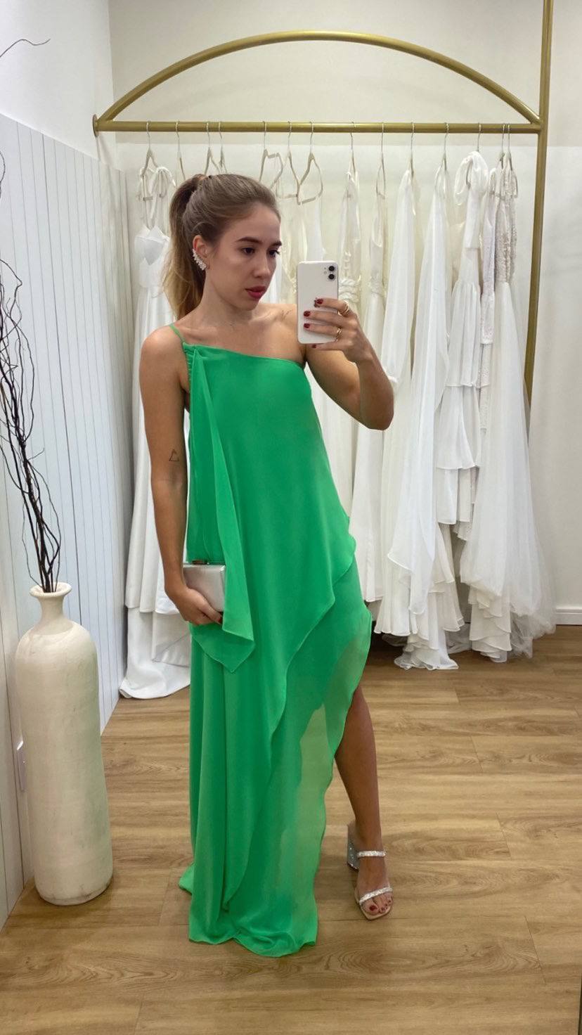 Vestido longo verde em tecido leve, com decote um ombro, caimento fluido e saia assimétrica com fenda.