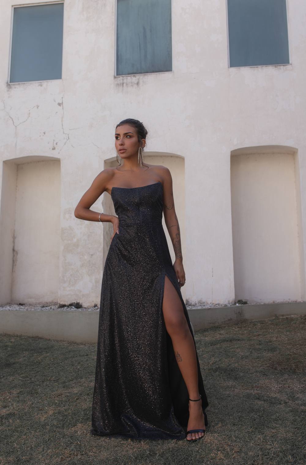 Vestido longo preto com brilho, modelo tomara que caia, fenda lateral alta e saia evasê.