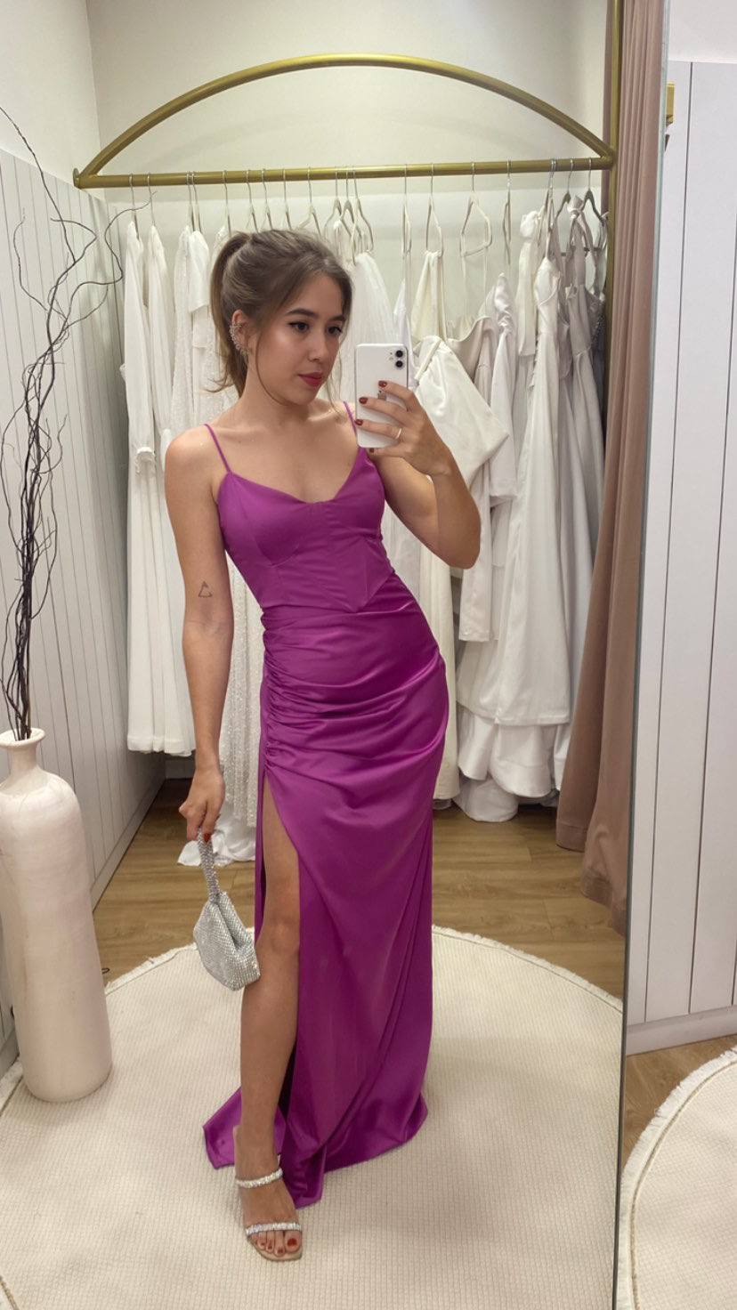 Vestido longo fúcsia de cetim com alças finas, drapeado no quadril e fenda lateral.
