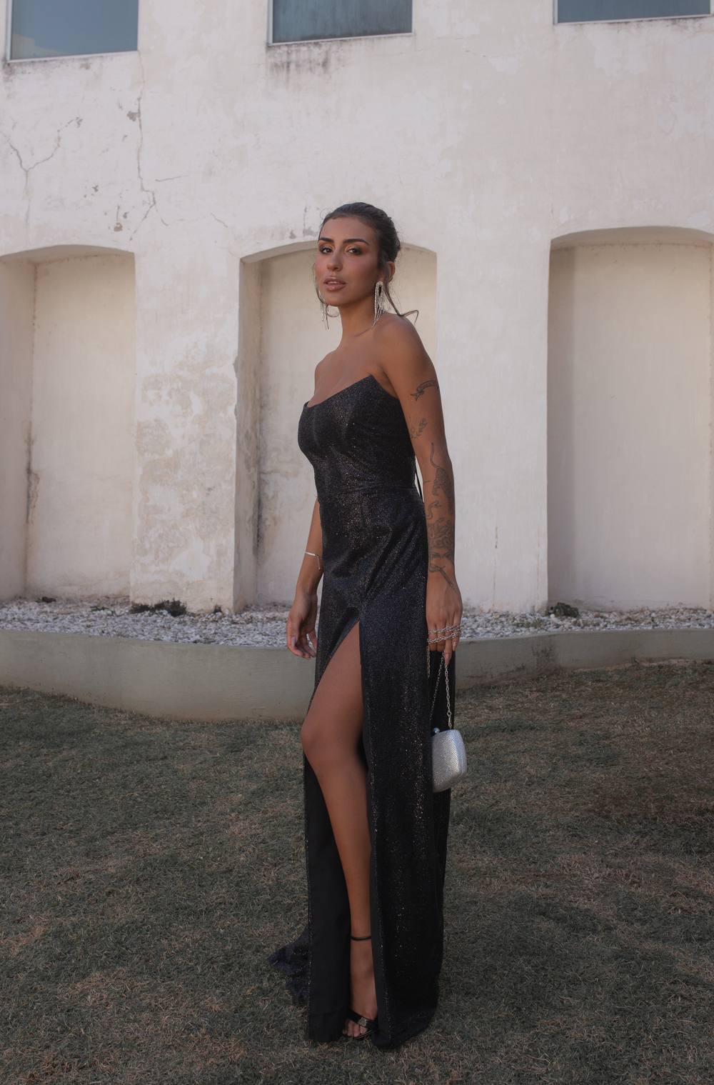 Vestido longo preto com brilho, modelo tomara que caia, caimento reto e fenda frontal alta.