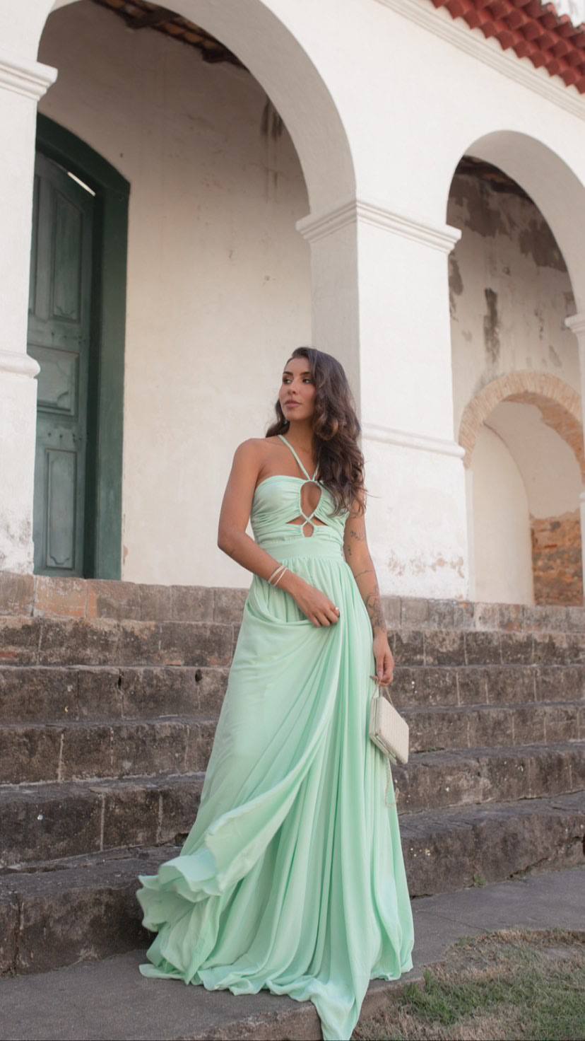 Vestido longo verde claro em tecido fluido, com decote frente única, recortes no busto e saia esvoaçante.