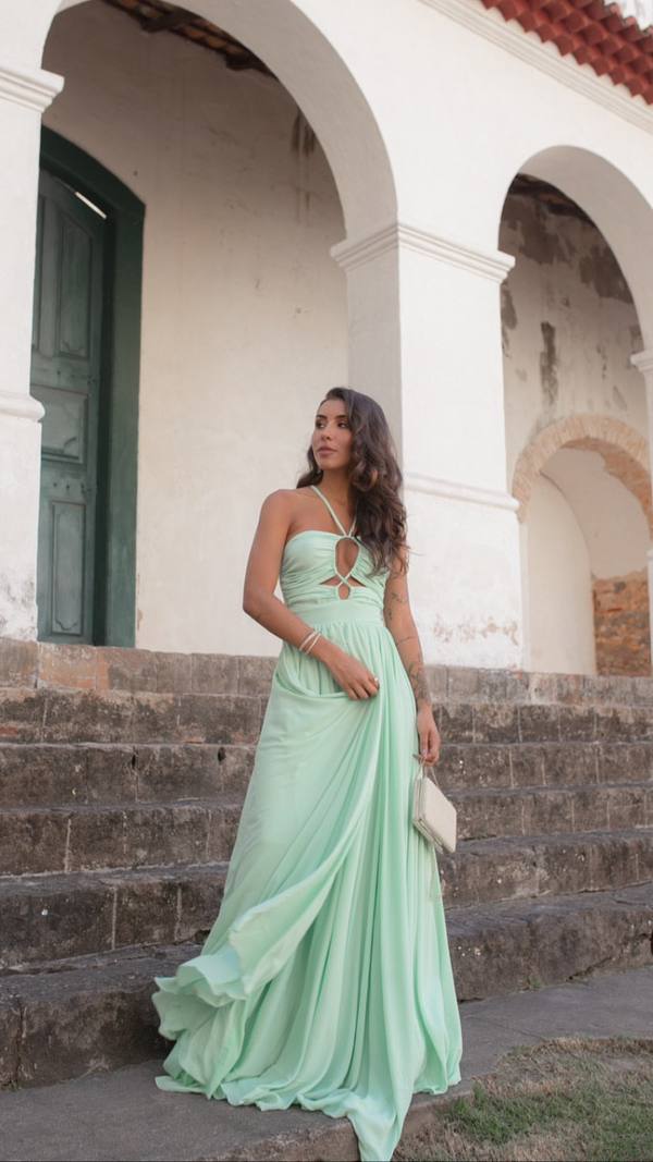 Vestido longo verde claro em tecido fluido, com decote frente única, recortes no busto e saia esvoaçante.