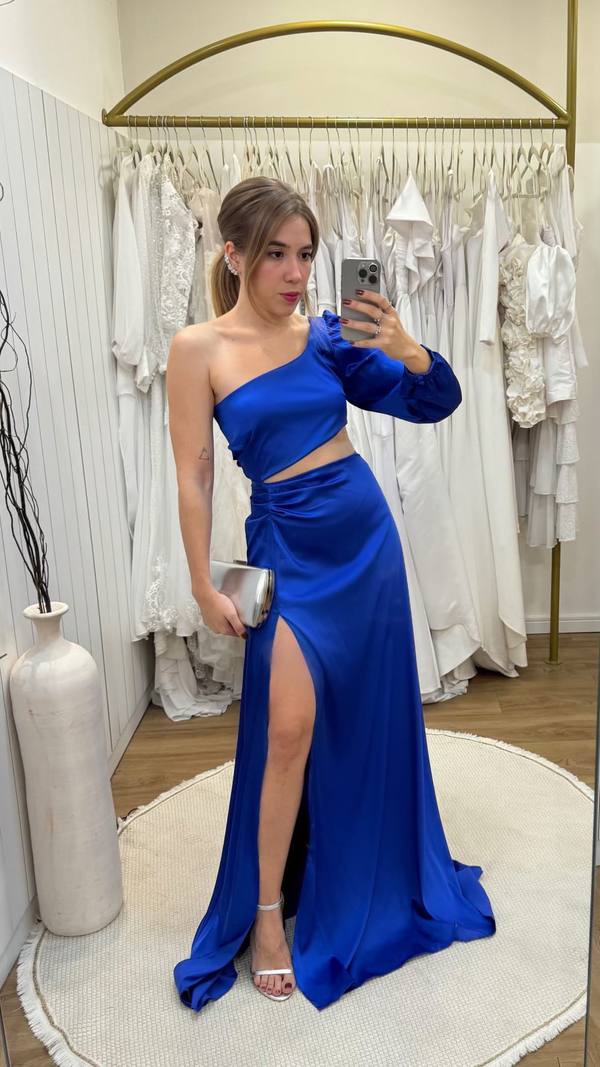Vestido longo azul de cetim, com decote de um ombro só, manga longa, recorte na cintura e fenda na saia.