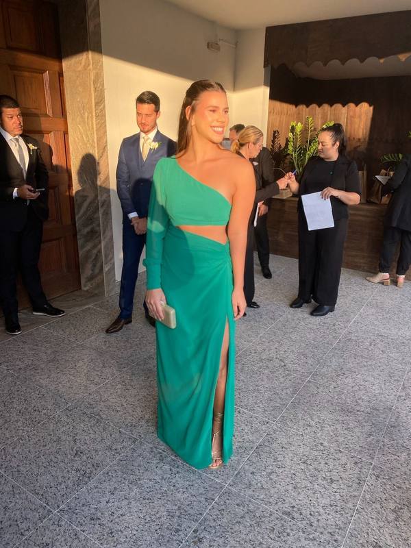 Vestido longo verde de um ombro só com manga longa, recorte vazado na cintura e fenda profunda na saia.