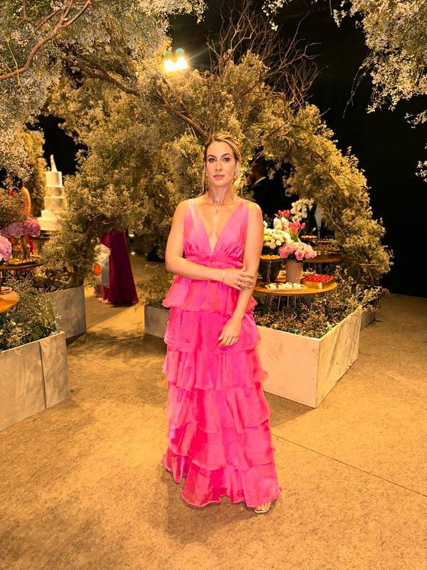 Vestido longo fúcsia com decote V profundo, saia fluida em camadas de babados e caimento leve.