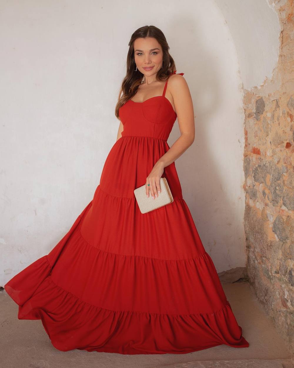Vestido longo vermelho com alças finas, decote estruturado e saia fluida em camadas.
