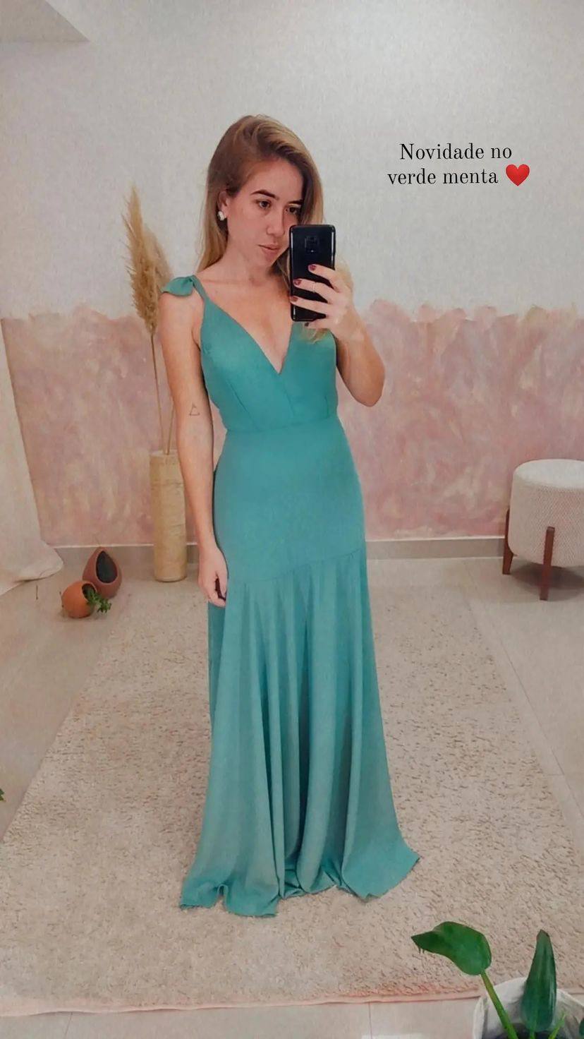 Vestido longo verde menta com decote V, alças finas com laço e saia ajustada no quadril.