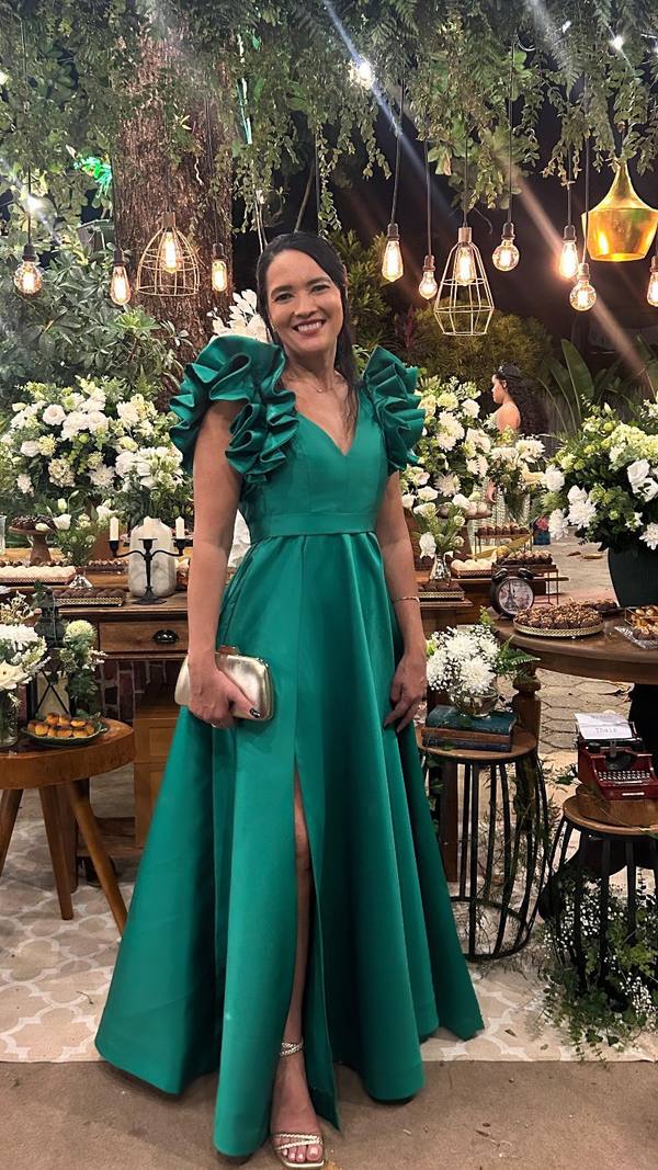 Vestido longo verde de cetim com decote V, detalhes babados nos ombros, saia evasê e fenda frontal.