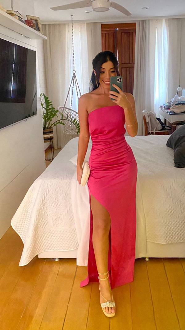 Vestido longo fúcsia tomara que caia em tecido acetinado, com modelagem ajustada, detalhe drapeado e fenda lateral.