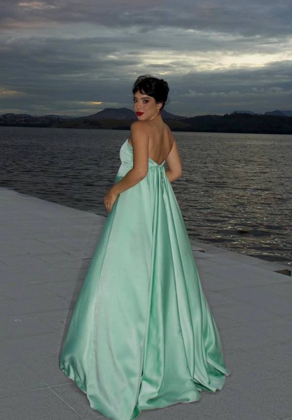 Vestido longo verde claro de cetim, modelo tomara que caia com costas abertas e saia ampla evasê.